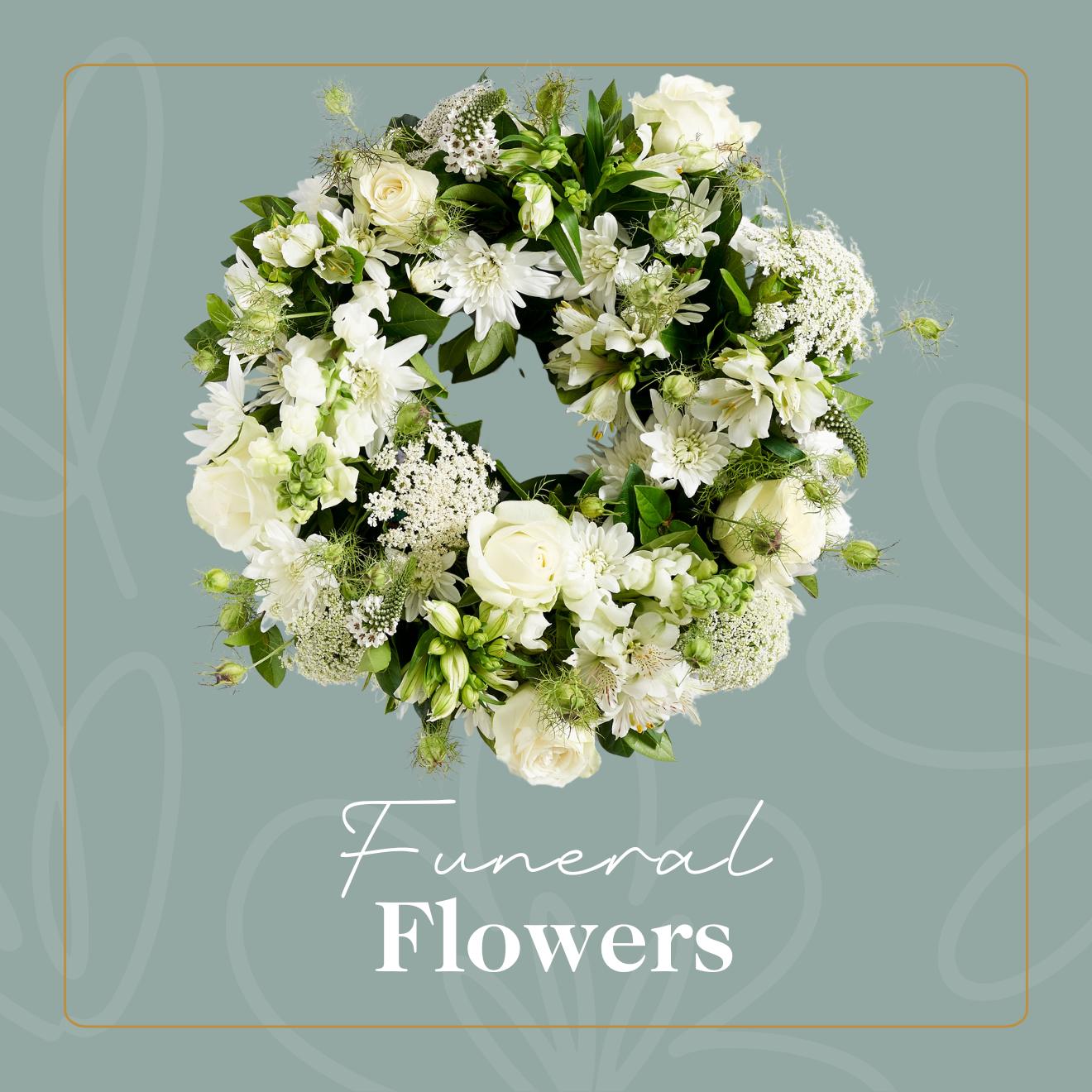 Funeral Flowers by Fabulous Flowers & Gifts – elegant white floral wreath with roses, lilies, and greenery on sage background