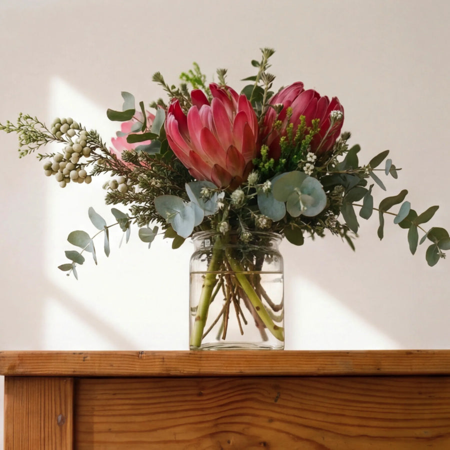 Cape fynbos posy in a glass jar on a wooden table, indigenous flower gift from Fabulous Flowers Claremont studio