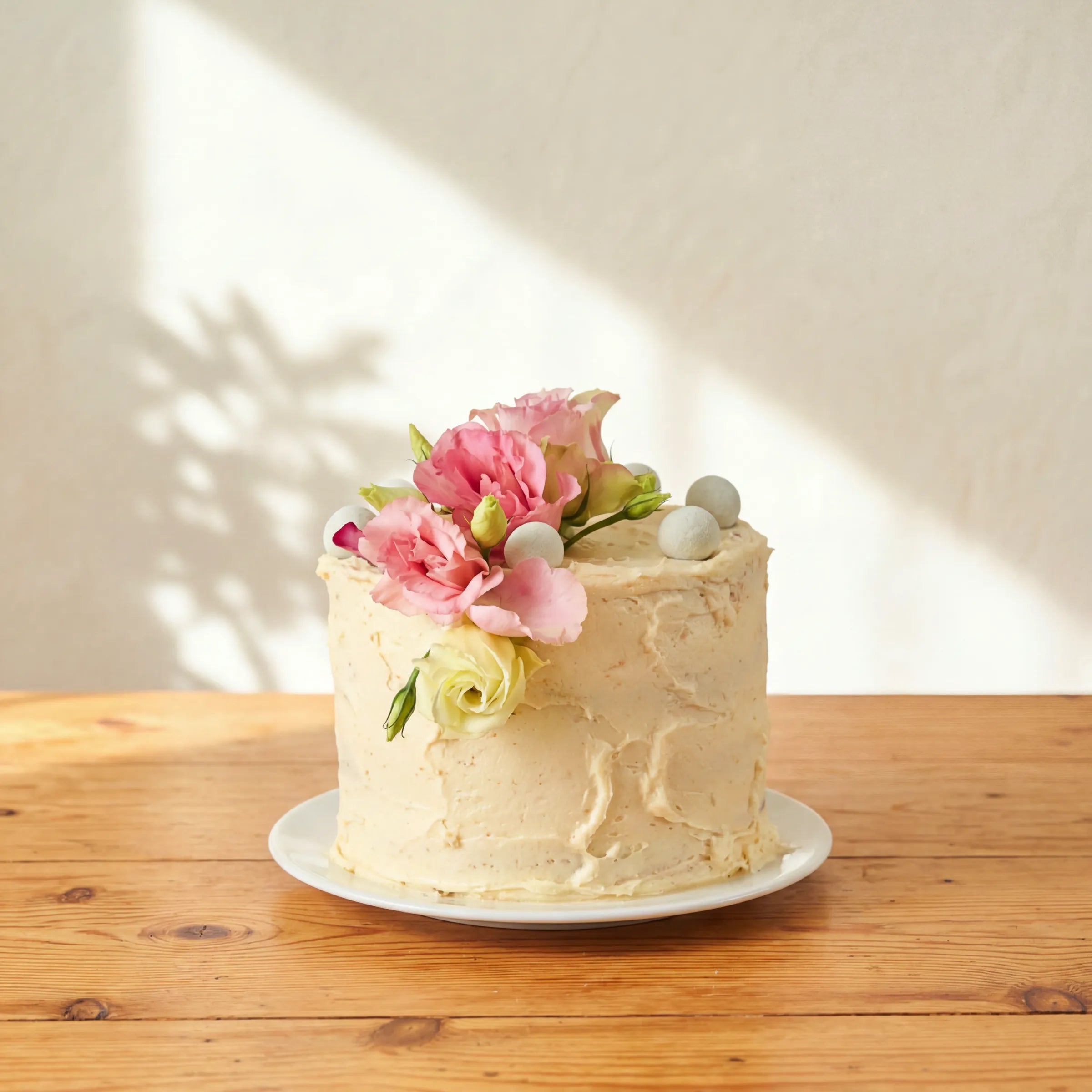 Garden Tea Party Cake with pink lisianthus, cream rose and pale chocolate pearls on rustic buttercream finish