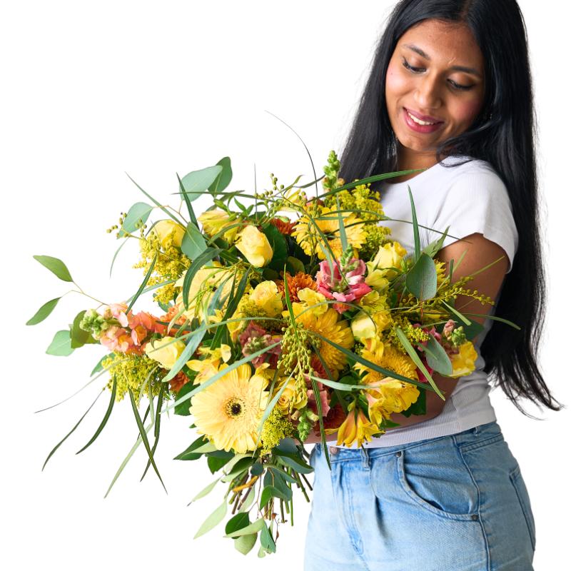 Women holding a big  yellow and orange bouquet of flowers smiling