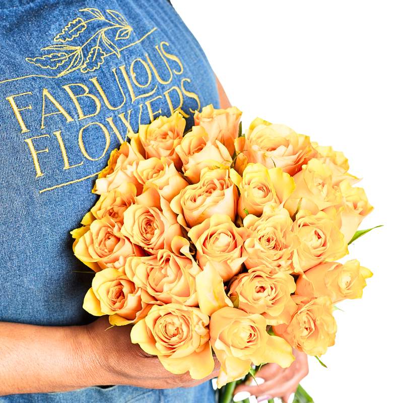 Bouquet of yellow roses held by a person wearing a blue shirt with 'Fabulous Flowers' branding.
