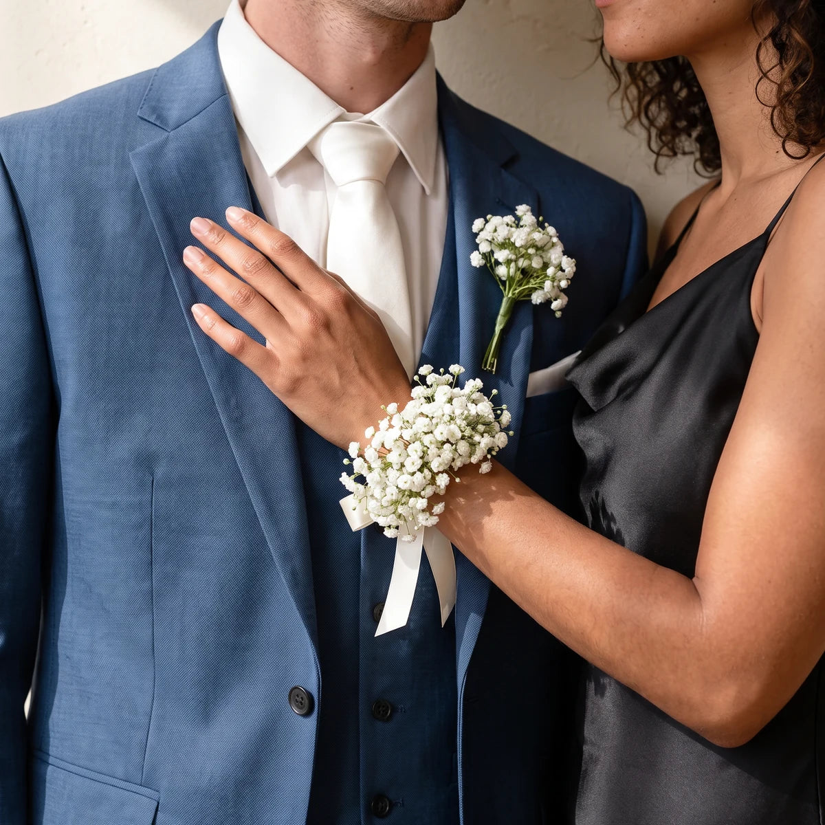 Couple in a blue suit and black dress wearing a matching baby's breath boutonniere and corsage, Fabulous Flowers South Africa