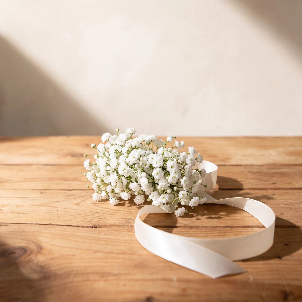 Baby's breath wrist corsage with an ivory satin ribbon on a pine table, Fabulous Flowers South Africa