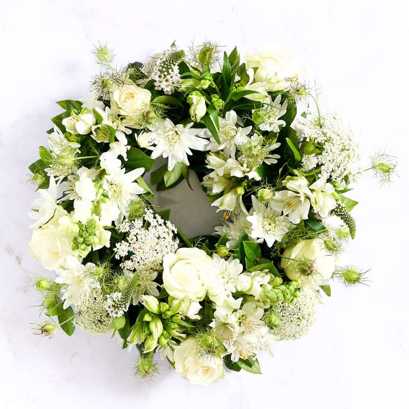 Heavenly Grace White Wreath with white roses, lilies, gerberas and soft greenery arranged as a sympathy tribute