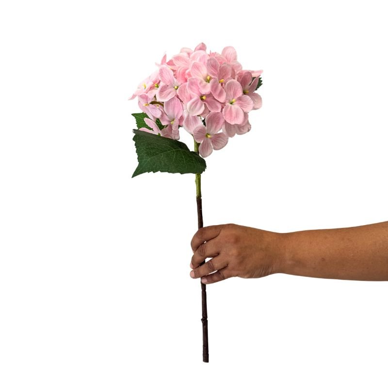 Hand holding a pink artificial flower stem against a white background
