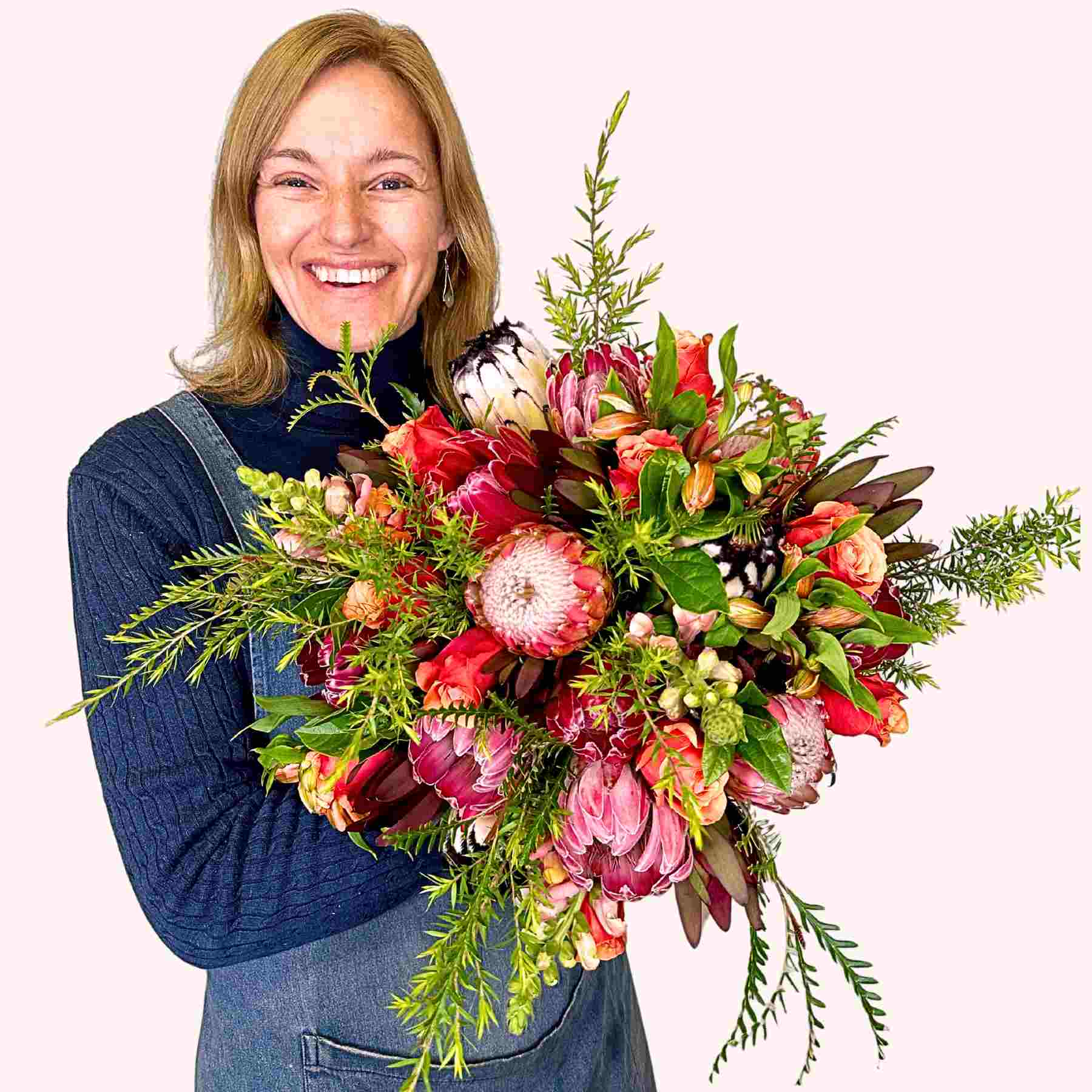 Joyful Jayne presenting her vibrant bouquet with red and pink flowers including proteas, named Jayne's Flower Bouquet from Fabulous Flowers and Gifts.