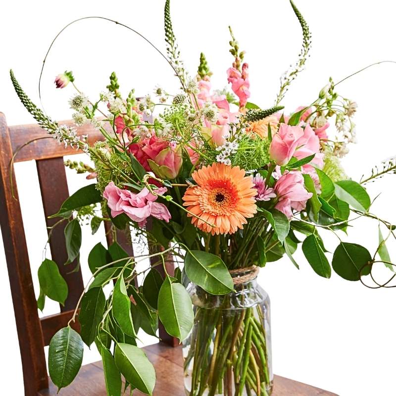 Close-up of Joy in a Large Jar showing soft pastel flowers, airy stems and lush green foliage in a glass jar