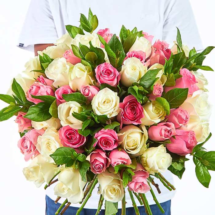 Kindness in Bloom bouquet with 60 long-stem pink and white roses with lush greenery, hand-tied in a full round shape