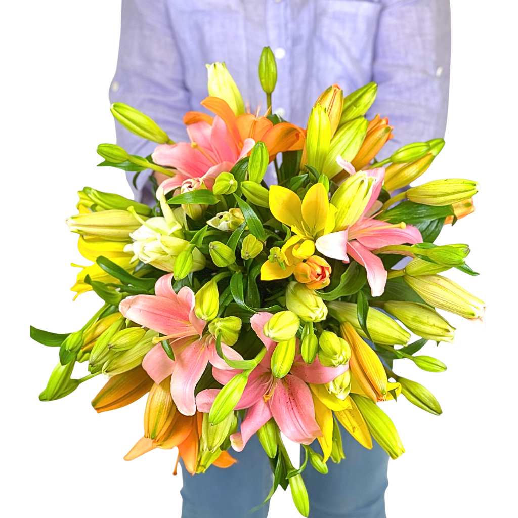Kiss Blush Lily Bouquet held by a person, featuring pastel lilies in pink and yellow tones with fresh greenery