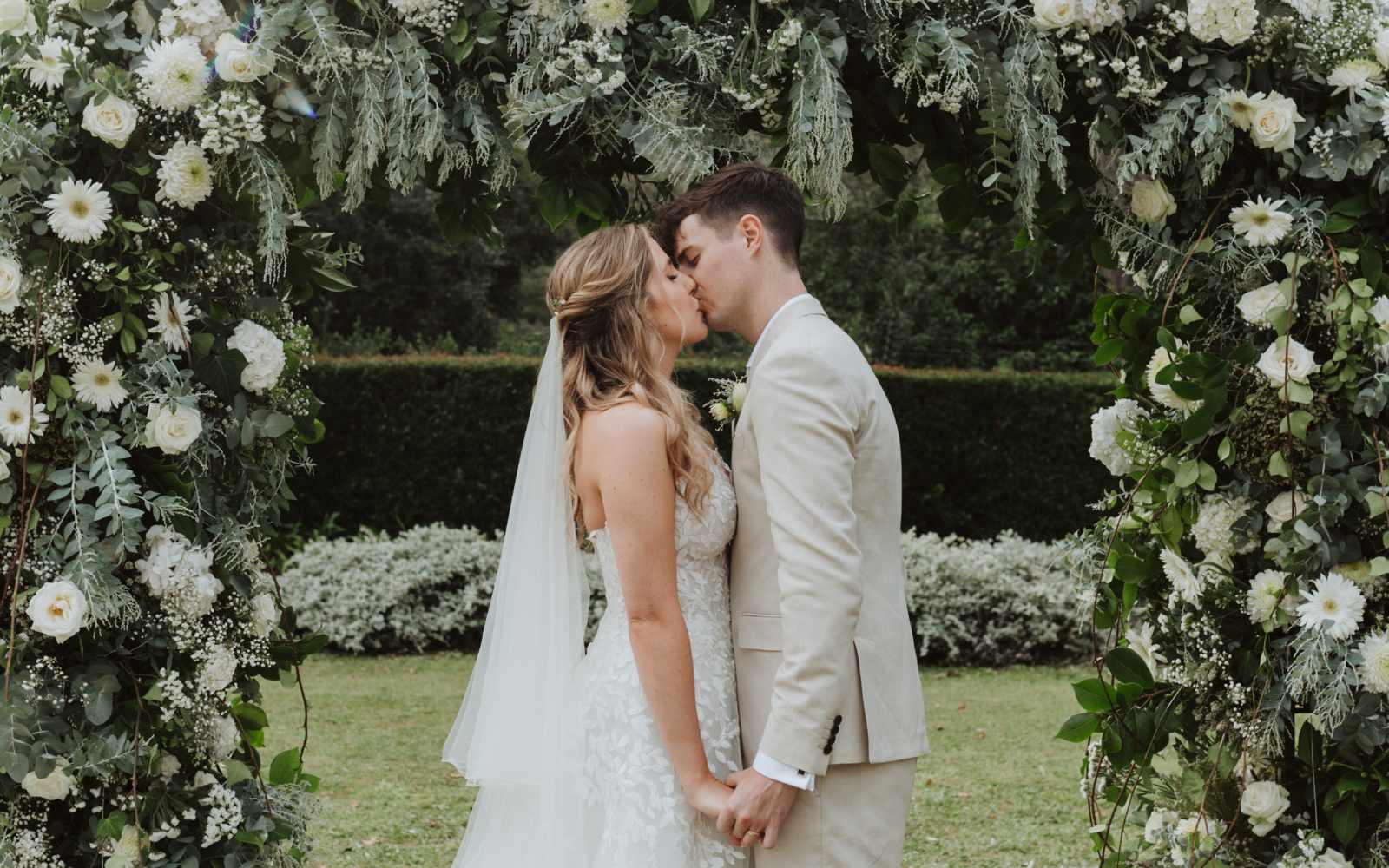 Just got married, couple kissing, flower arch, white roses, white gerberas - Fabulous Flowers