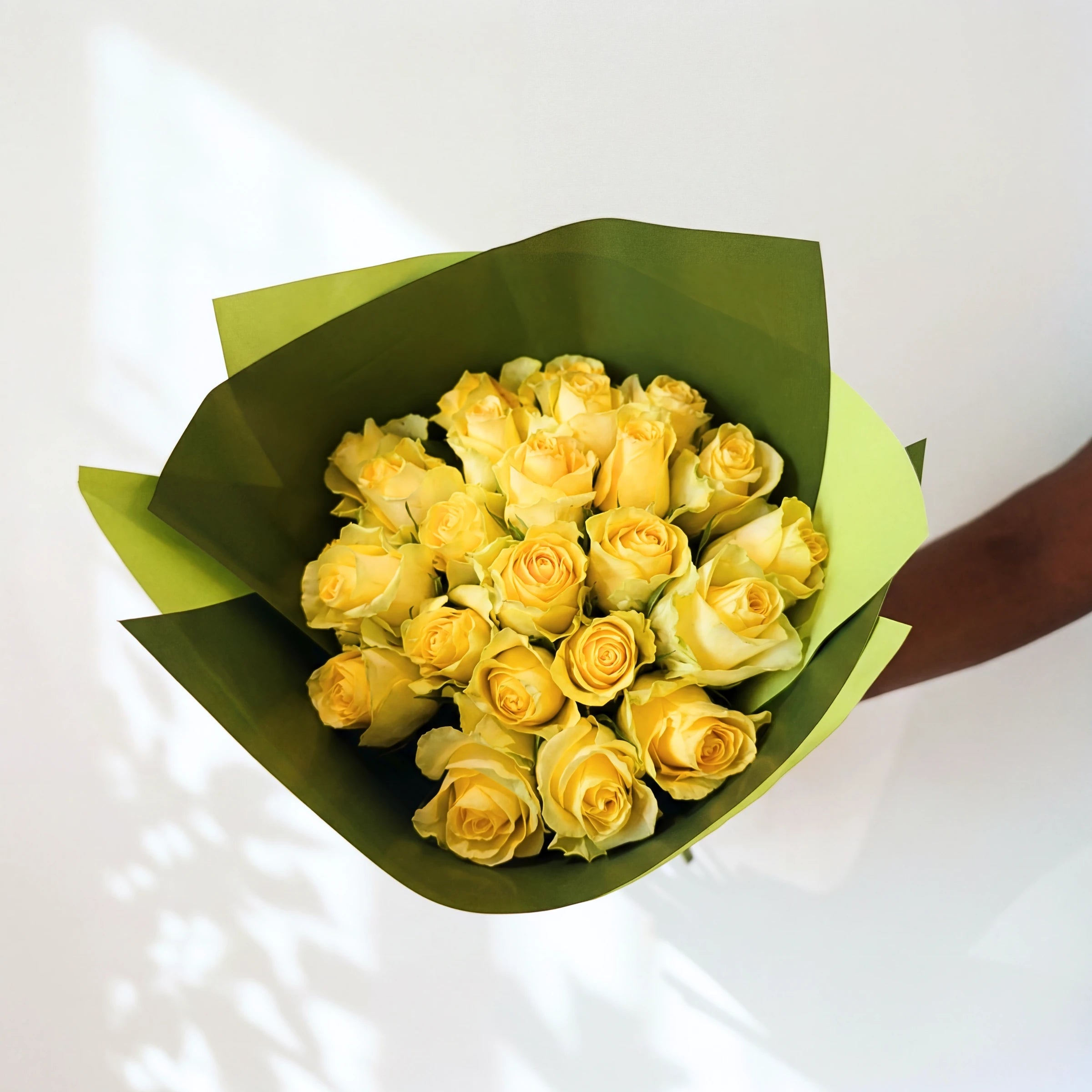 Two dozen yellow roses, the Lemon Drop bouquet seen from above in green wrap
