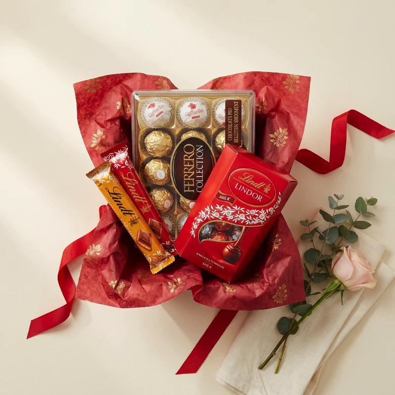 Lindt vs Ferrero gift box overhead with Ferrero Collection, Lindt Lindor Milk and Lindt Caramel in red and gold wrap, Fabulous Flowers and Gifts