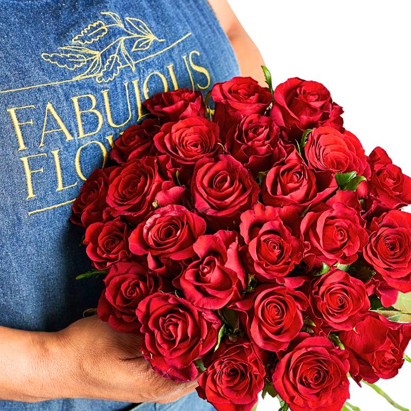 Person holding a bouquet of red roses with 'Fabulous Flowers' shirt in the background