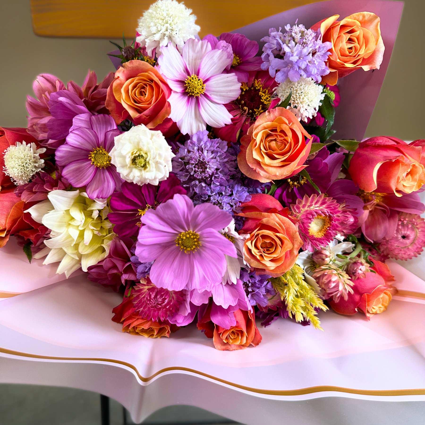 Close-up of the Lush Wonder Flower Bouquet featuring a vibrant assortment of roses, daisies, and other seasonal blooms, wrapped in a stylish pink paper, available at Fabulous Flowers and Gifts.