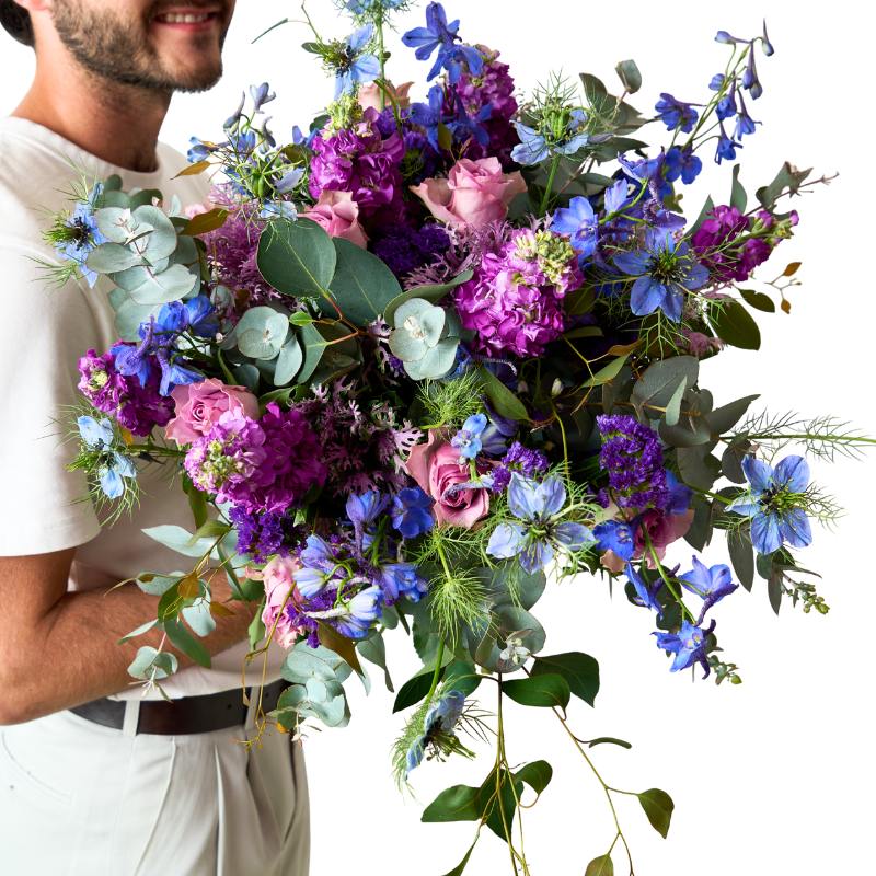 Man holding a vibrant bouquet of flowers with a white background