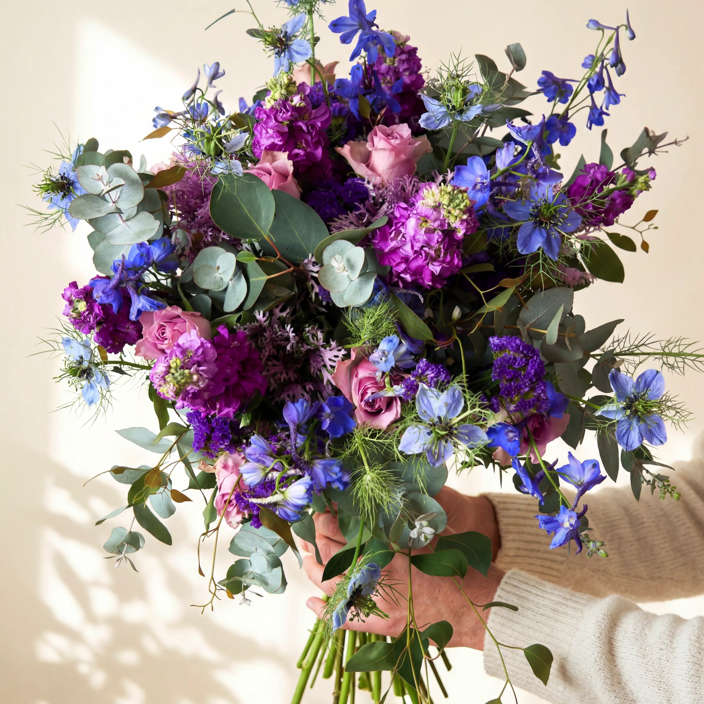 Overhead view of the purple and blue lavender garden bouquet with pink roses, stock, delphinium, nigella and eucalyptus
