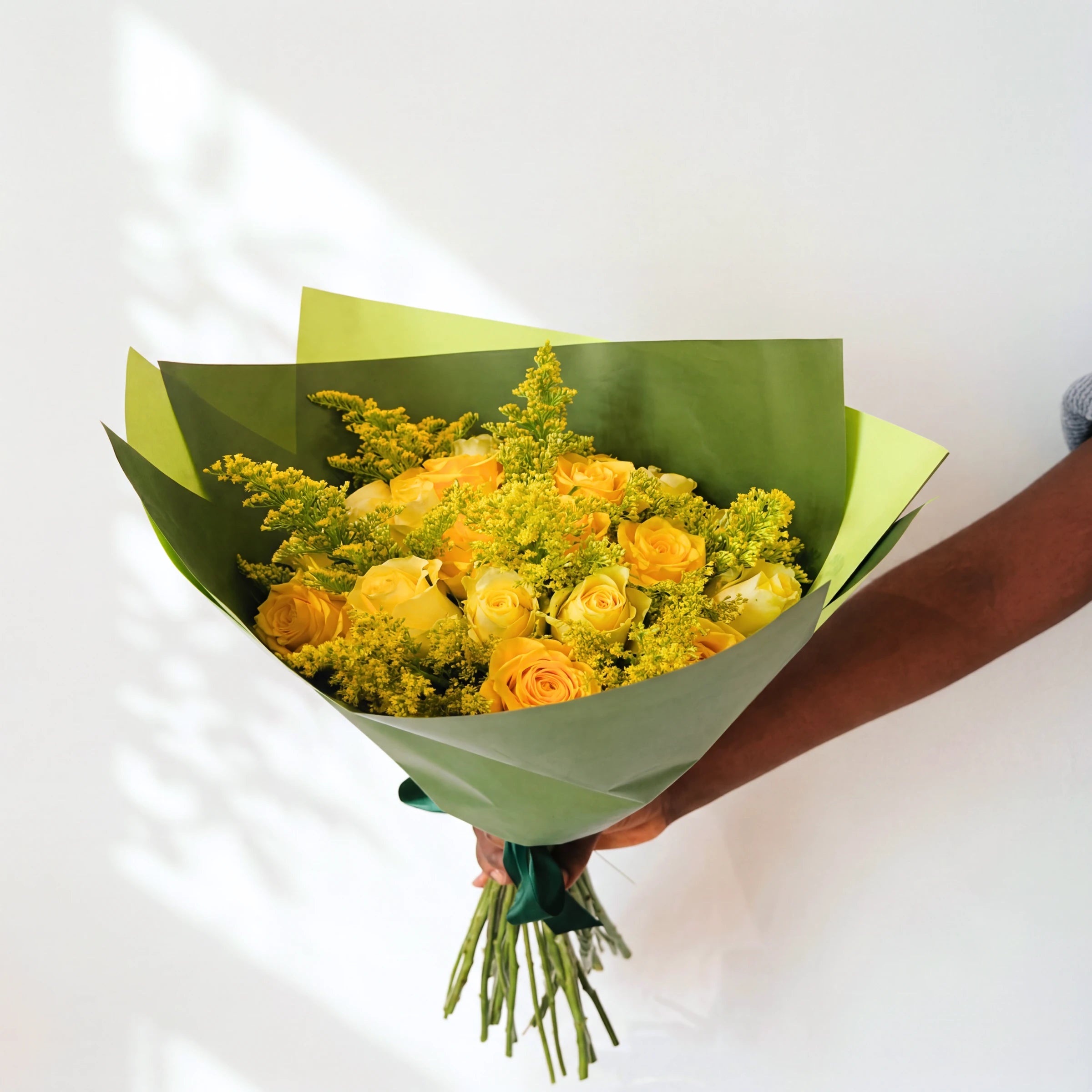 Top-down view of the Meadowlark bouquet, yellow roses and golden solidago in green wrap