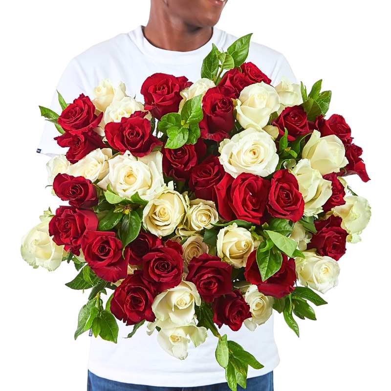 Person holding a large red and white rose bouquet with lush greenery