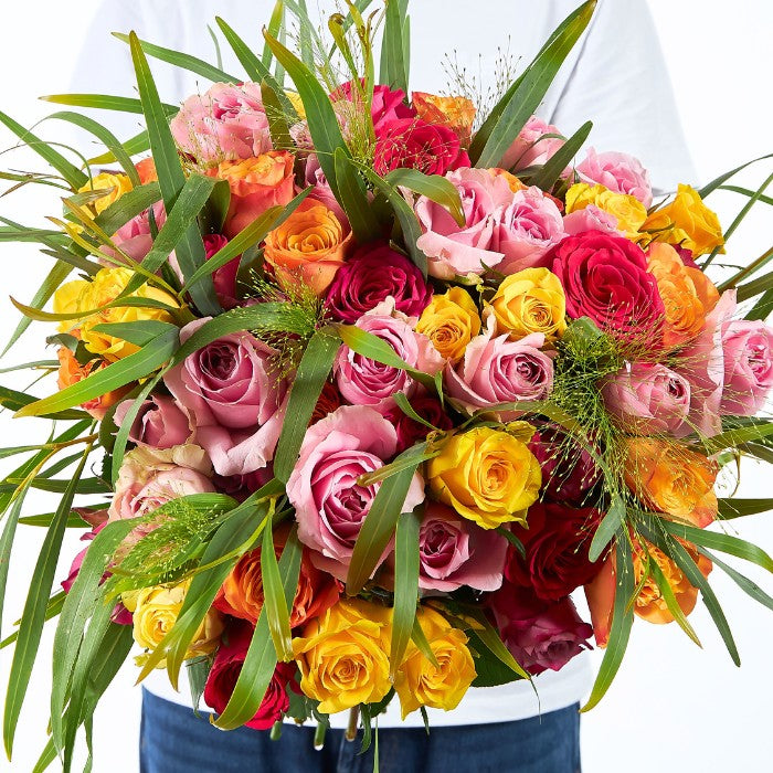Mixed Rose Bouquet – colourful roses in pink, red, orange and yellow tones held by a smiling man in a white shirt.