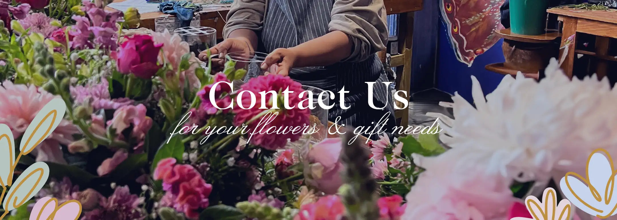 Florist arranging a variety of vibrant flowers, including pink roses and other blossoms, in a workshop setting. Contact us for your flowers and gift needs. Fabulous Flowers and Gifts.