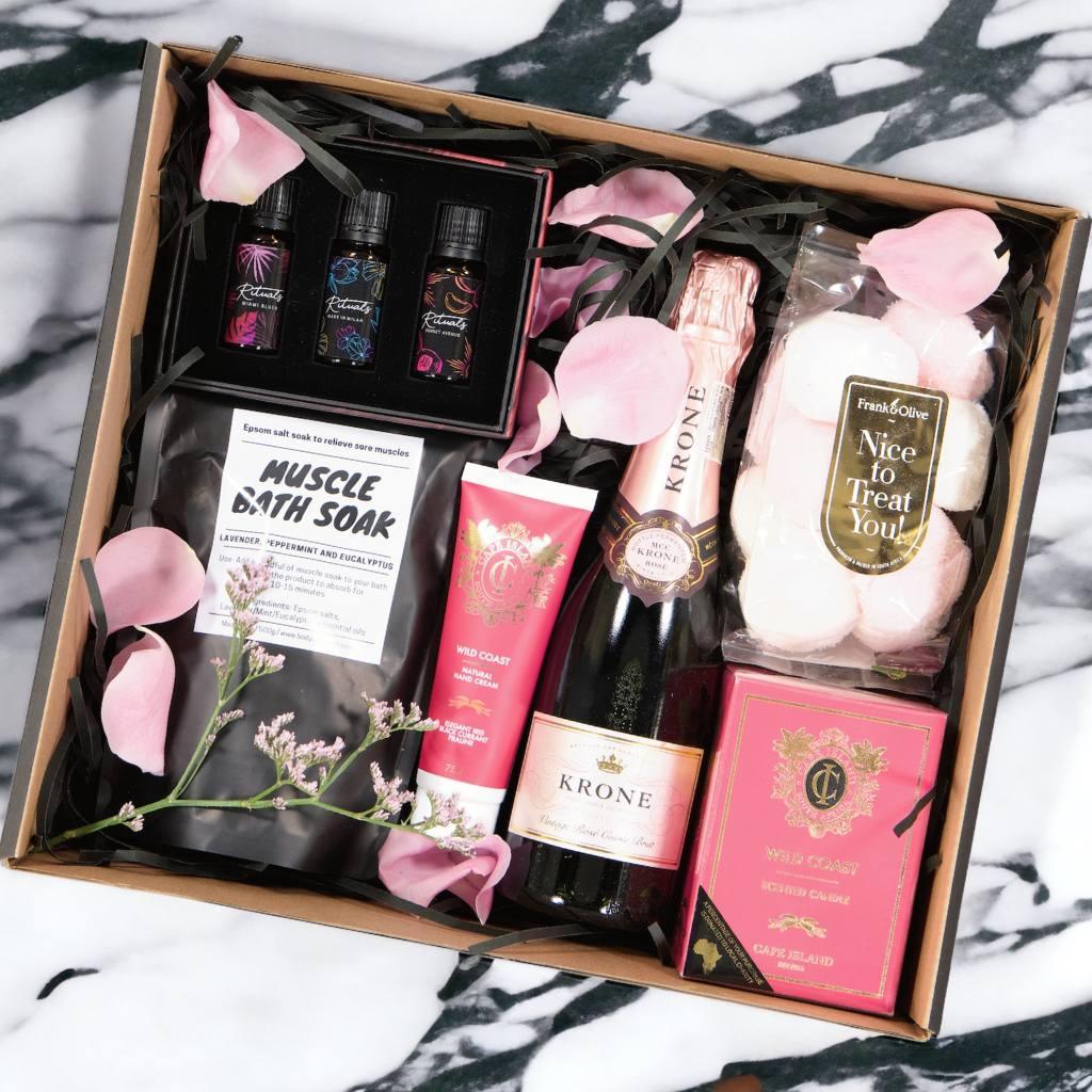 The Pamper and Indulge Gift Box for Girls includes Muscle Bath Soak, Krone Brut Rose MCC 375ml, Cape Island Wild Coast Hand Cream and Candle, Frank & Olive marshmallows and a trio of Aura Rituals Essentials Oils - Fabulous Flowers