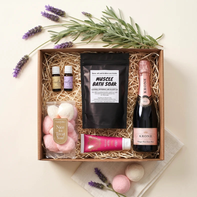 Pamper and Indulge gift box for her flat-lay with Krone Vintage Rosé, muscle bath soak, Firefly essential oils, Wild Coast hand cream, Frank & Olive marshmallows and bath bombs, Fabulous Flowers and Gifts