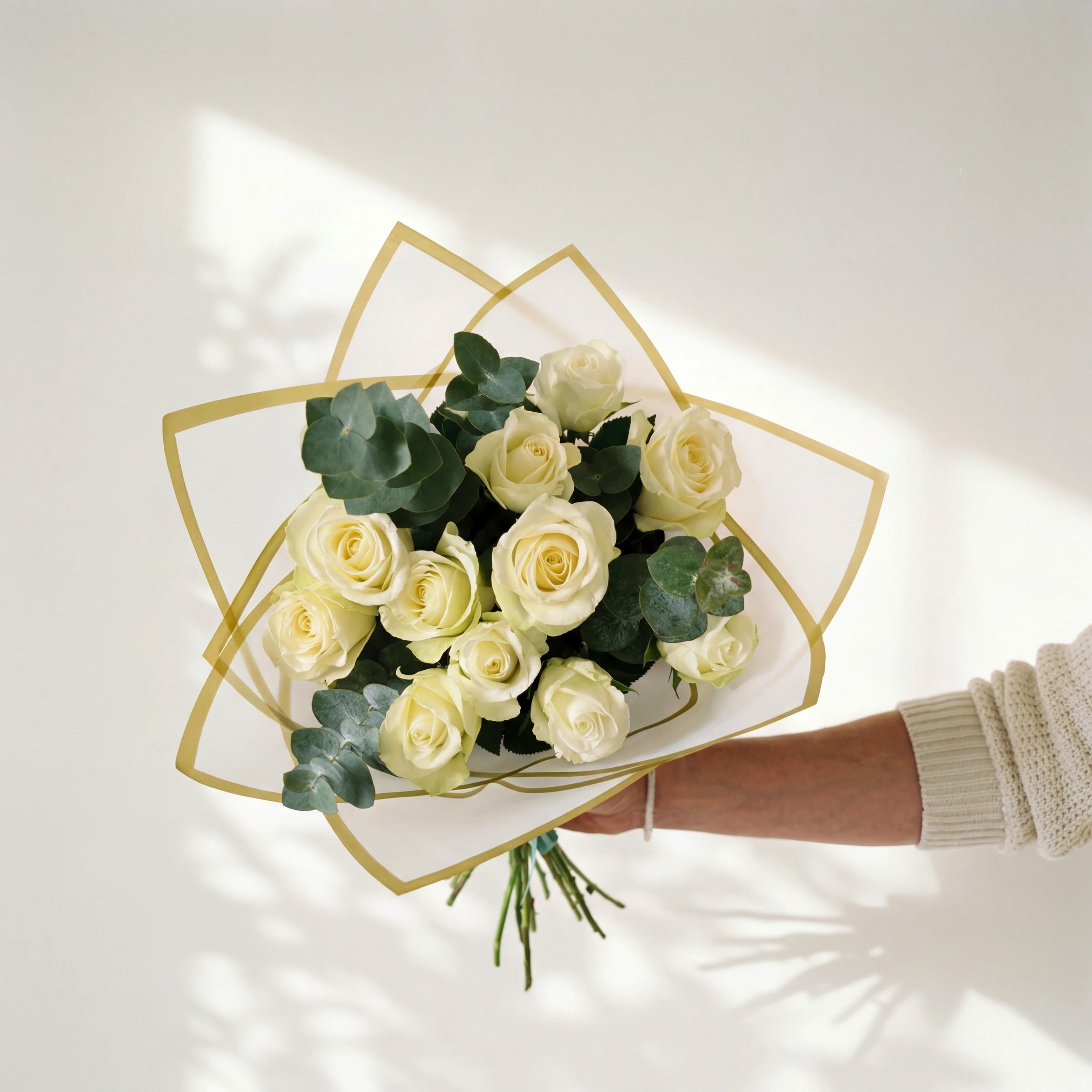 Pearl and Sage, a dozen white roses with silver-dollar eucalyptus in a cream and gold wrap, held by Fabulous Flowers