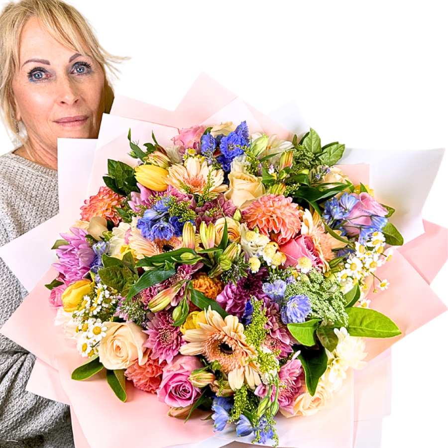 Woman holding a large, colorful bouquet of flowers against a white background