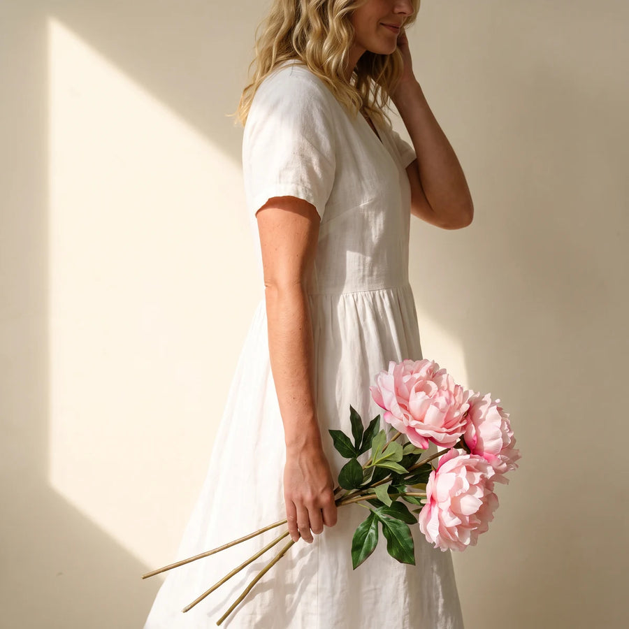 Woman carrying three pink silk peony stems, a long-lasting flower gift