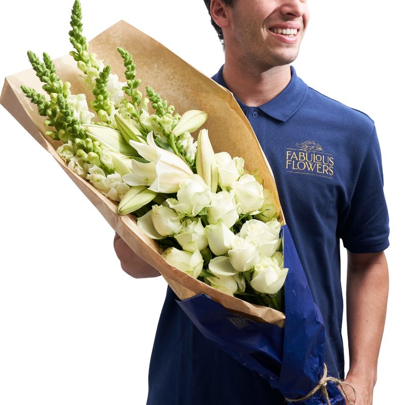 Man holding a bouquet of flowers wrapped in brown paper, wearing a blue shirt with 'Fabulous Flowers' logo.