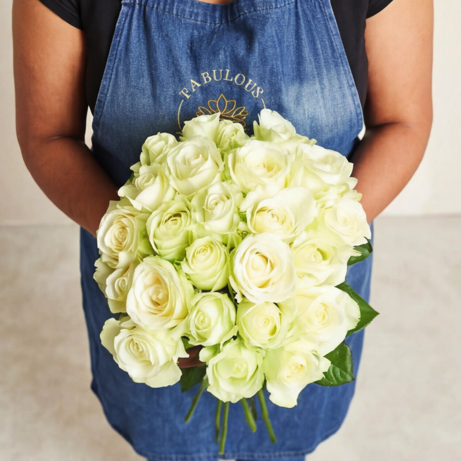 The Pure Snow rose bouquet, a round hand-tie of fresh white and cream roses with green leaves.