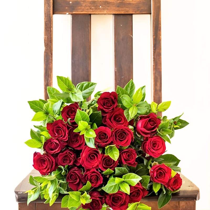 Bouquet of red roses with green leaves on a wooden chair