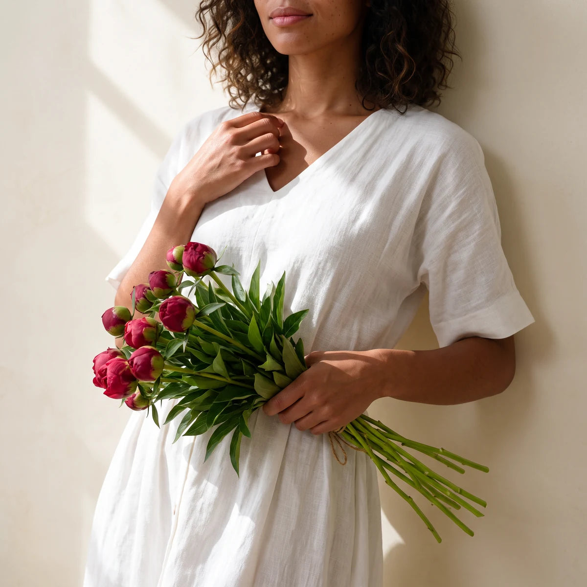 Woman holding a bunch of red peonies in bud, same-day red peony delivery in Cape Town