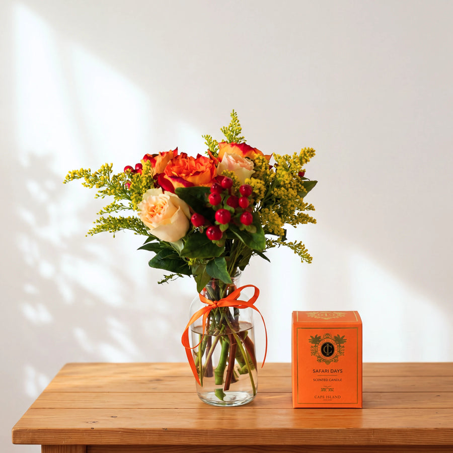 Savanna & Sun gift set with orange and cream roses in a vase beside a Cape Island Safari Days scented candle box