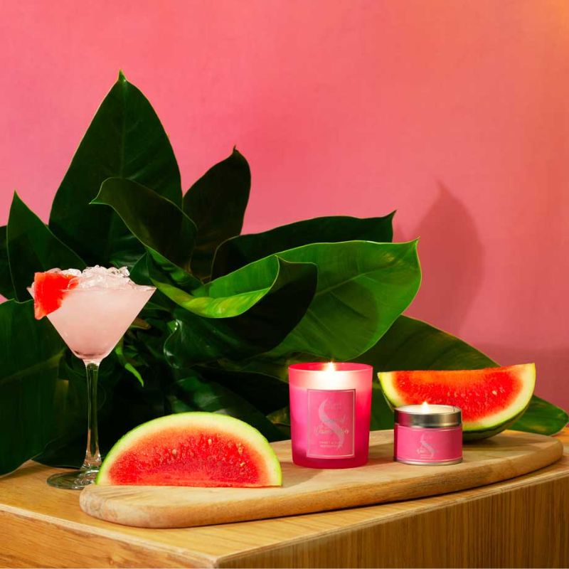 Pink candle and watermelon slices on a wooden board with a pink background