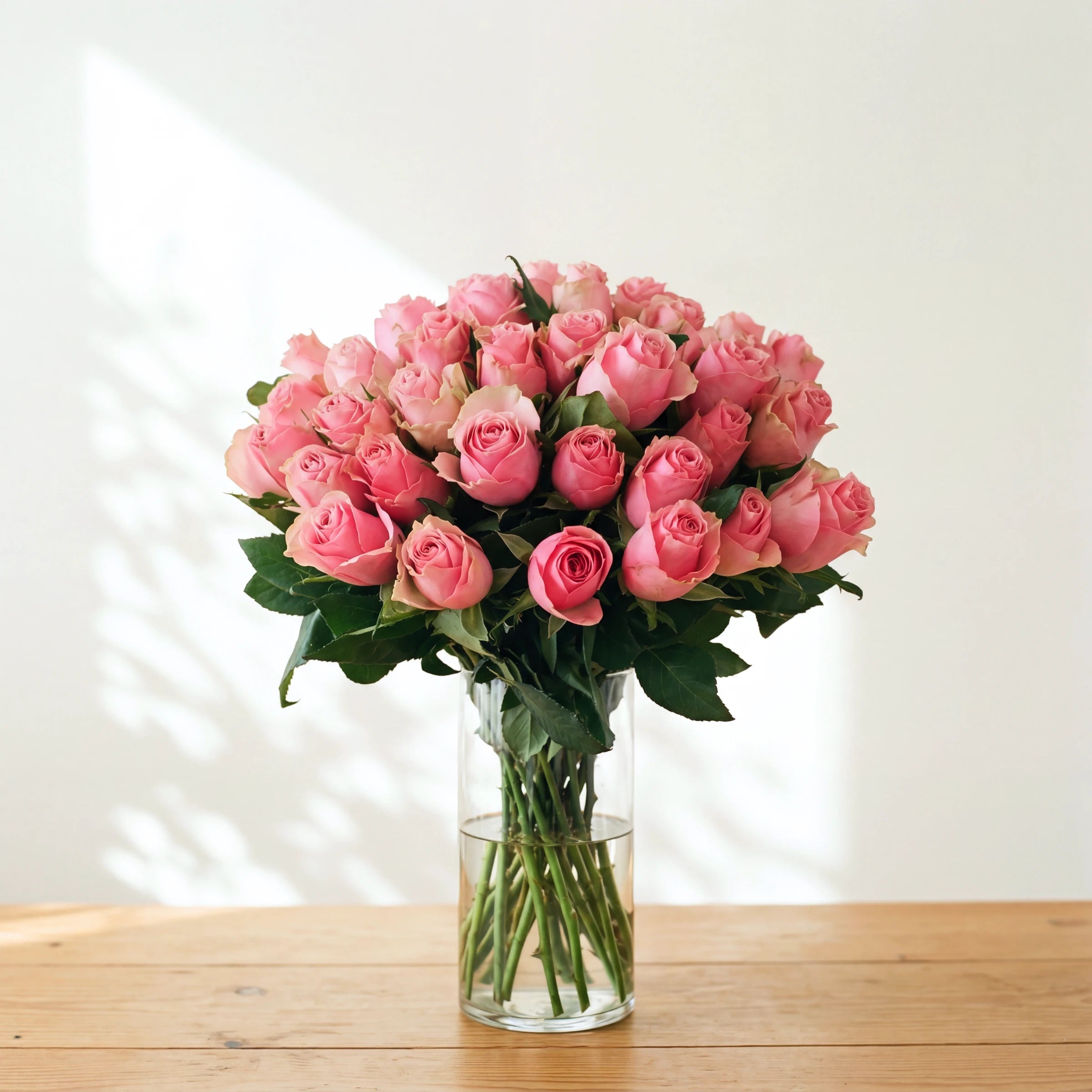 The largest Sherbert, a full vase of pink roses arranged in clear glass by Fabulous Flowers, ready to display