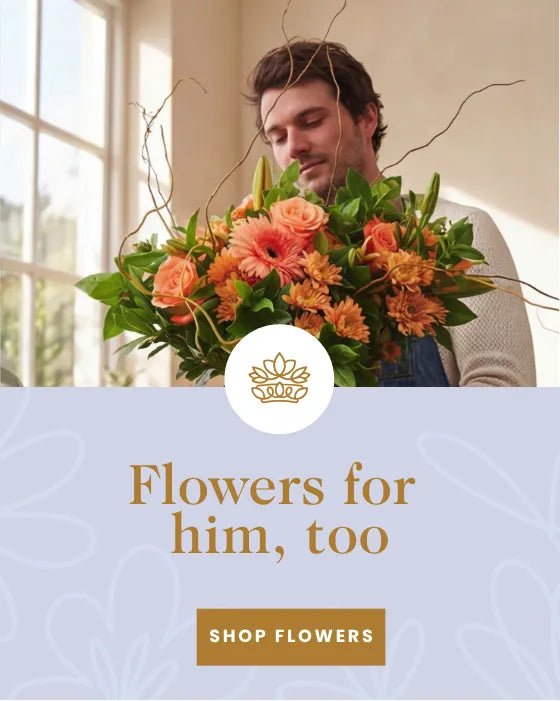 Man holding a lush orange flower bouquet in a sunlit kitchen