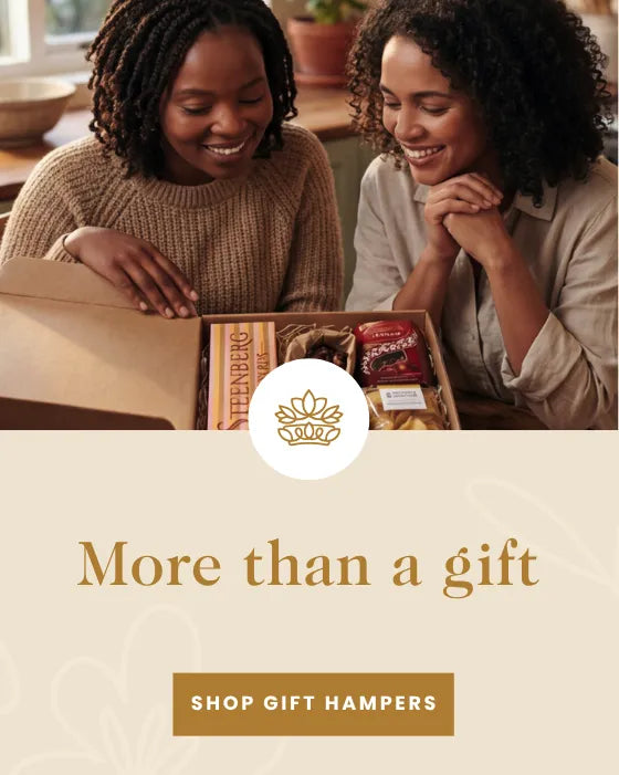 Two friends smiling at an open Fabulous Flowers gift hamper at a kitchen table