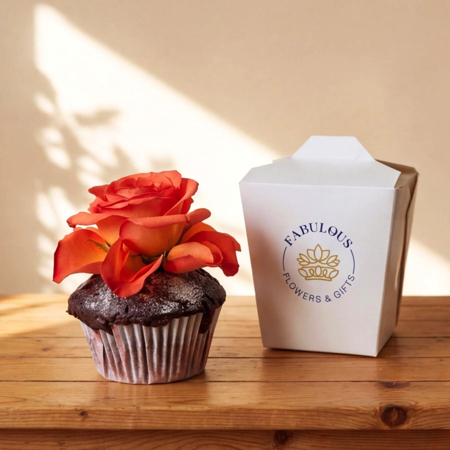 A single chocolate cupcake topped with a vibrant orange rose, sitting beside a white Fabulous Flowers branded gift box with the gold crown emblem, Cape Town same-day cupcake add-on