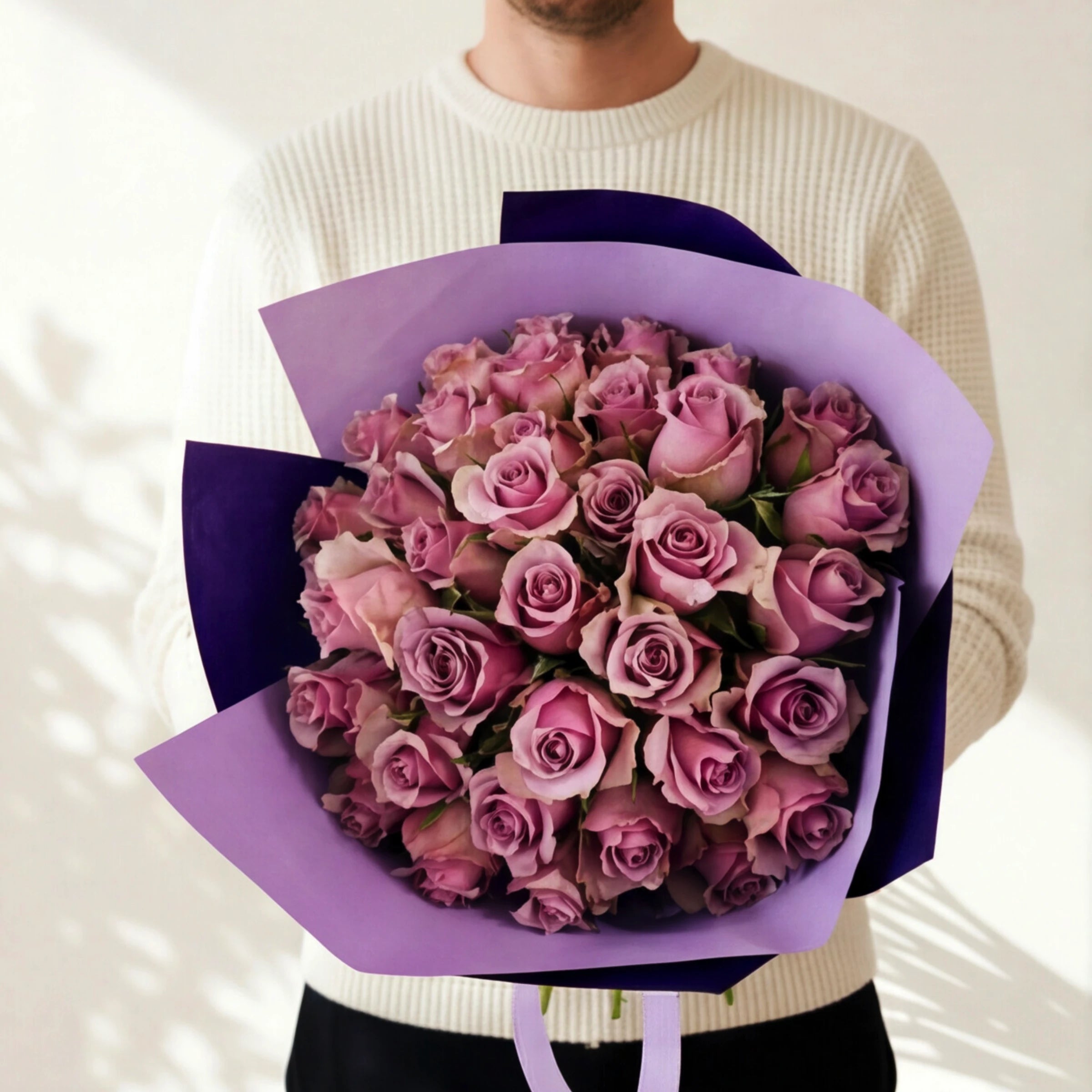 The largest Smitten, three dozen lavender roses in purple wrap, held by a Fabulous Flowers florist