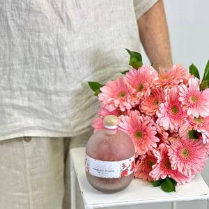 Pomegranate Vanilla Bath Crystals as an Add On with 20 soft pink gerbera daisies being held by model - Fabulous Flowers