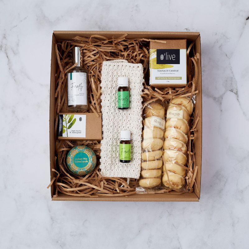 Luxury gift set with Firefly room spray, essential oils, soy wax candle, O'live massage candle, handmade soap, and almond biscuits.