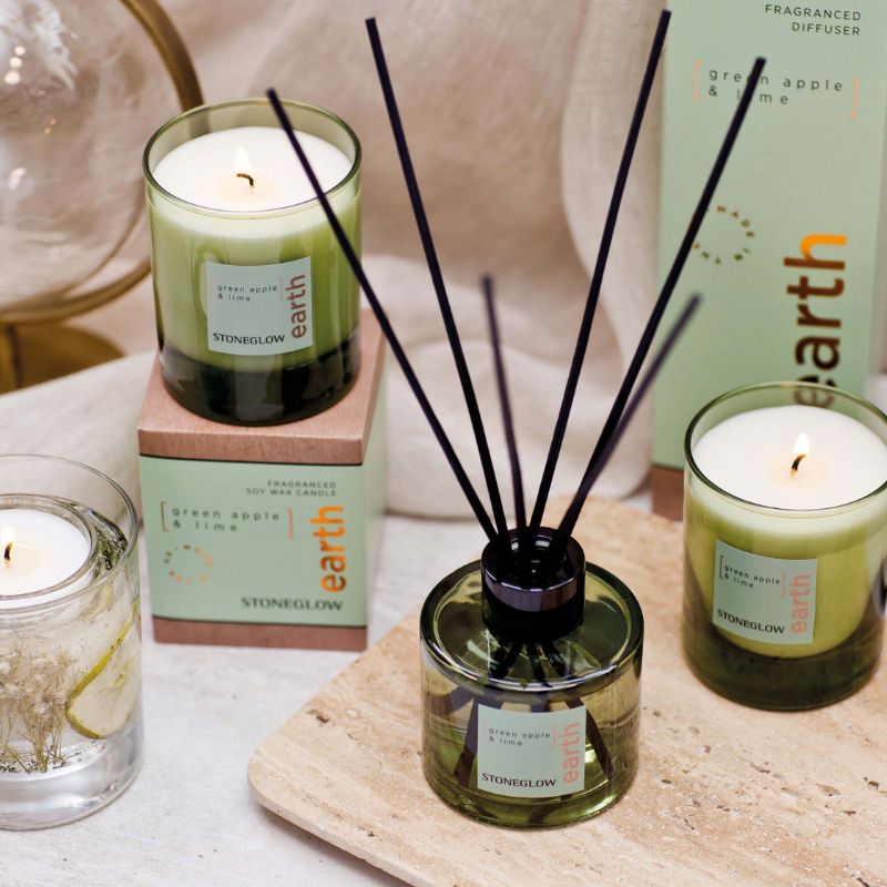 Stoneglow diffuser and candles on a wooden surface with 'earth' branding.