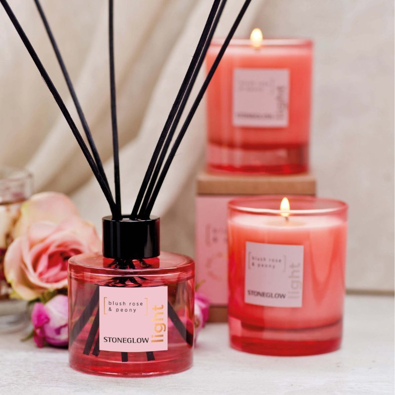 Two lit candles and a diffuser with 'Stoneglow' branding on a surface.
