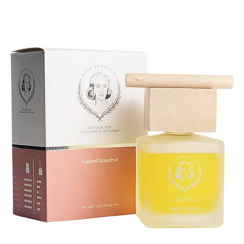 Yellow fragrance diffuser with wooden top and packaging on a white background