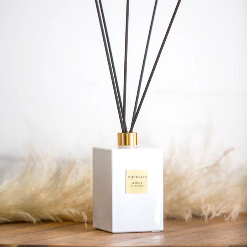 White diffuser bottle with black reeds on a wooden surface with pampas grass