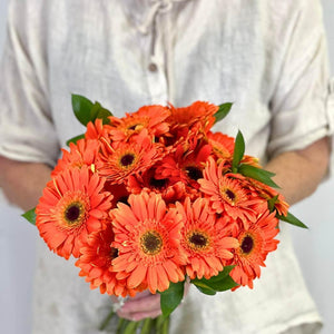 Florist holding Sunburst Gerbera Daisy Flower Bouquet with 20 orange gerberas and greenery - Fabulous Flowers
