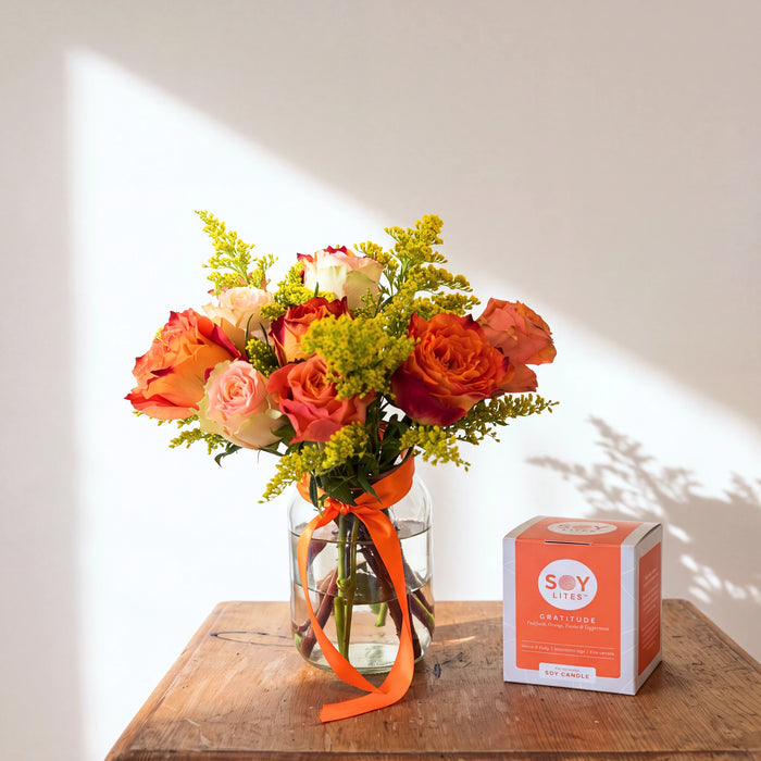 Sunlit Gratitude orange and peach rose arrangement with golden solidago and Soy Lites candle