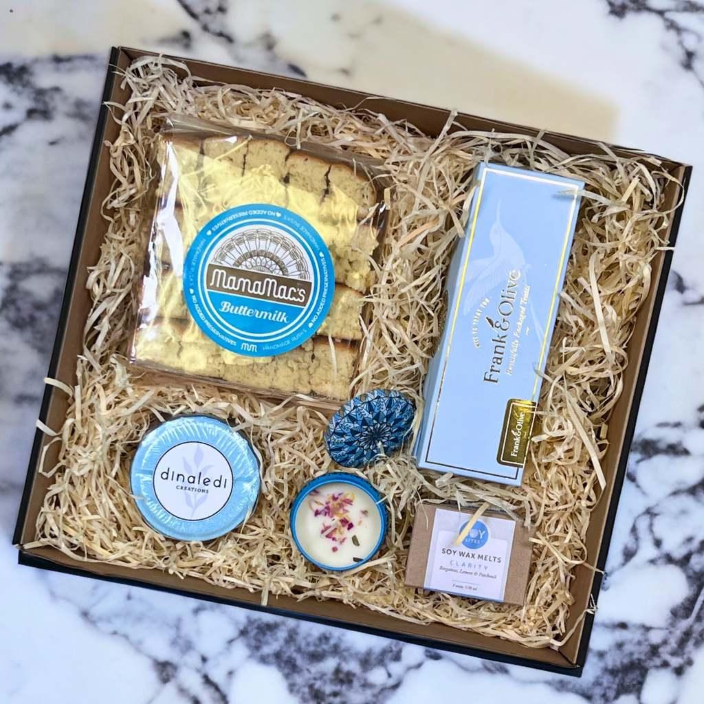 Christmas gifts arranged in a gift box that include caramels, soy wax melt, bath pill, buttermilk rusks and a fragranced candle - Fabulous Gifts
