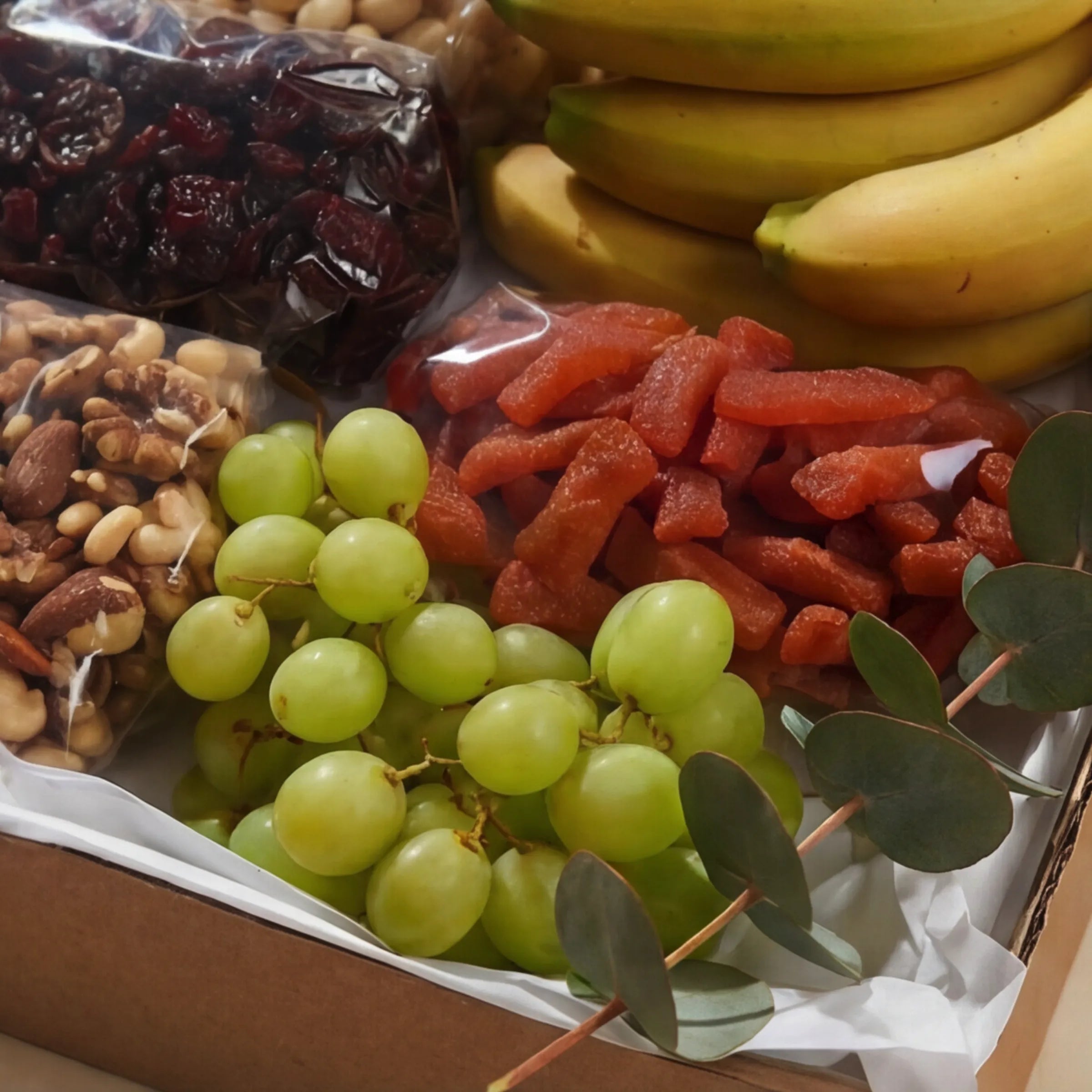 Close-up of The Healthy Collection contents from Fabulous Flowers South Africa, dried cranberries, mixed nuts, meeboos, fresh bananas and green grapes, a fruit and nut gift box and get-well hamper for Cape Town delivery